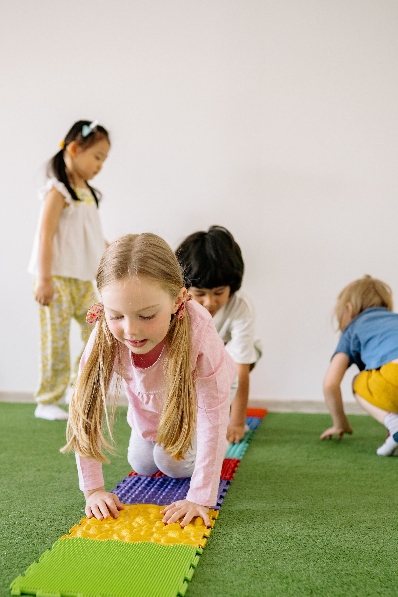 Children crawling along colorful textured activity mats