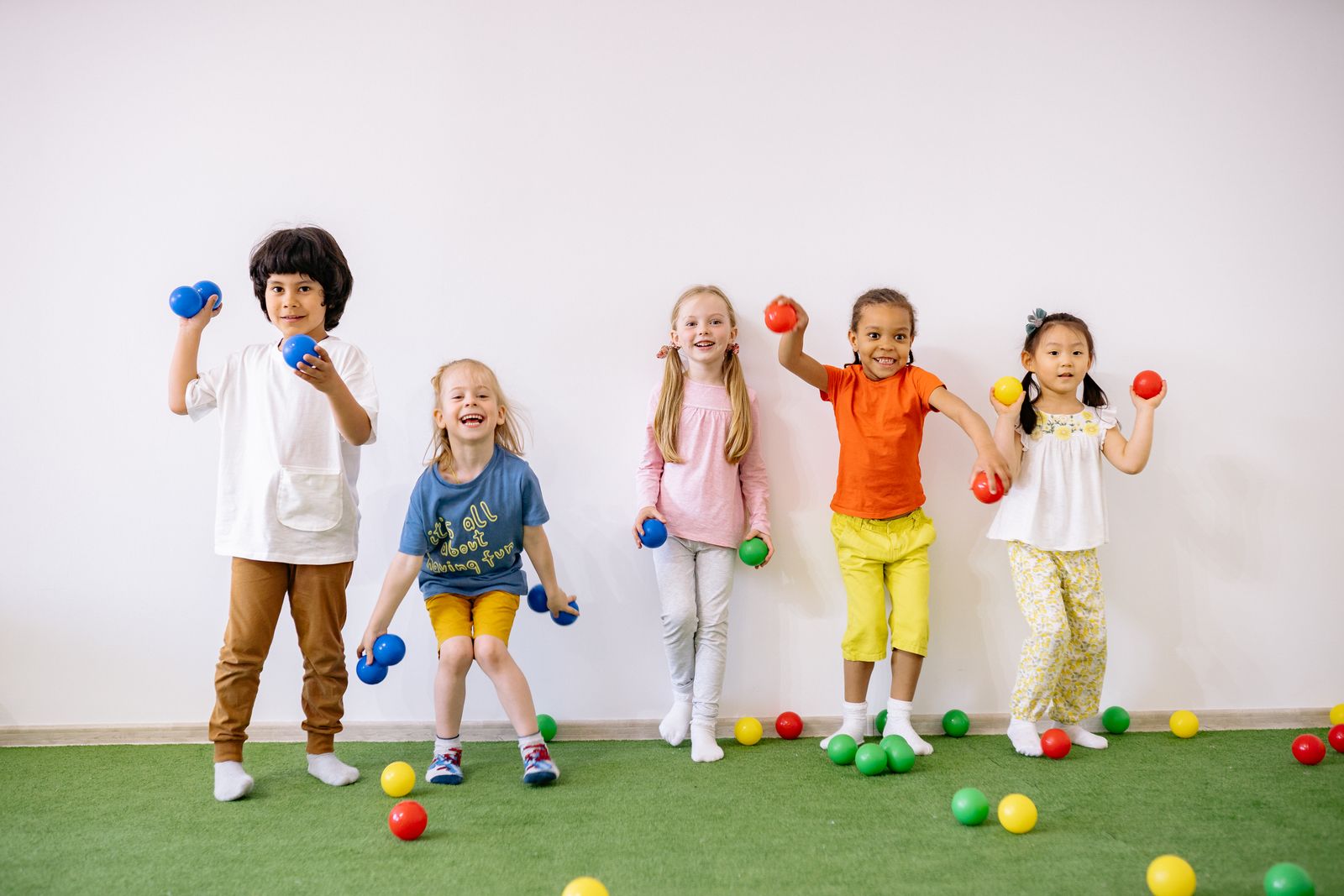 Children moving and playing together with colorful balls